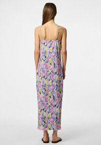 Vestido maxi con estampado de flores que presenta tirantes ajustables, un corte relajado y pliegues verticales en colores pastel sobre un fondo claro.