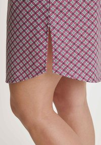 Musterrock in Rosa und Weiß mit geometrischen Formen. Verfügt über einen seitlichen Schlitz am Saum für zusätzliche Details. Der Stoff wirkt leicht.