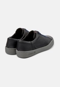 Sneakers in pelle nera con finitura testurizzata, suole in gomma grigia, lacci blu e dettagli di cucitura pronunciati. Logo del marchio sul lato.