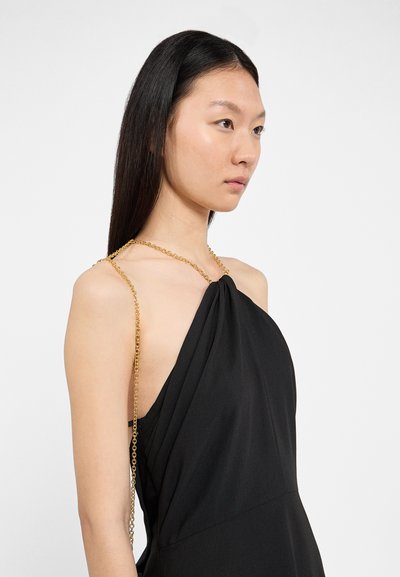 Črna obleka z vratnim izrezom in naglavnim trakom, ki se ponaša s prepletenim dizajnom, gladko teksturo in zlatim verižnim poudarkom ob rami za dodatno podrobnost.