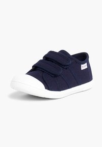 Tumes sinine kanvasjalats, millel on kaks Velcro-riba, valge kummine varbaosa ja tekstuuriga valge välispind. Lihtne disain, ilma nähtavate mustriteta.