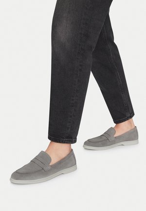 Šedé semišové boty na slip-on s texturovaným designem, světlou gumovou podrážkou a horizontálními akcenty, doplněné černými zúženými džíny.