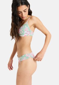 Květinový bikiny set s světle zeleným základem, zdobený růžovými a bílými květinovými vzory. Vrchní část má trojúhelníkový tvar a nastavitelné ramínka.