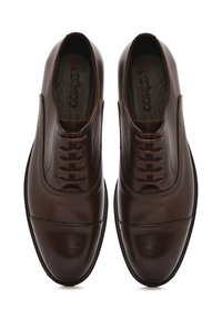Chaussures habillées en cuir marron avec une finition lisse, présentant un bout rond, un laçage à l'avant et des détails de couture subtils sur le dessus.