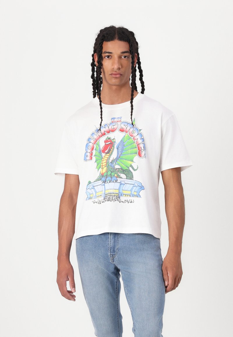 Tricou alb din bumbac, cu un grafic colorat Rolling Stones ce include un dragon și o scenă de concert. Mâneci scurte, croială lejeră, textură minimă.