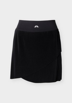 Sort plisseret nederdel med asymmetrisk kant og bred linning med lille hvidt logo midt for.