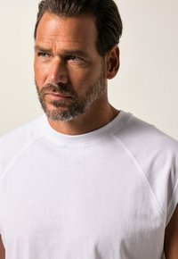 Witte mouwloze t-shirt met een ronde halslijn, zachte katoenen textuur en geribbelde details bij de hals en armgaten.