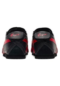 Czarno-czerwone buty sportowe z gładką skórzaną cholewką, teksturowanymi akcentami z zamszu i gumową podeszwą. Zawierają logo "Tiger" na pięcie.