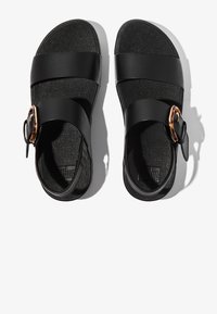 Sandalias negras con dos correas anchas y puntera redonda. Presentan una hebilla decorativa en un patrón carey. Plantilla texturizada.