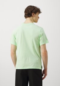 Mintgrøn kortærmet t-shirt i bomuldsstof, afslappet pasform, med rund hals og en lige kant med sideslidser.