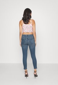 Blå skinny jeans med hög midja, kombinerat med en blommig kort topp. Tyget verkar vara denim och visar en kroppsnära design.