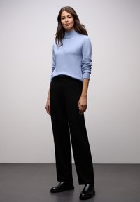 Jasnoniebieski sweter dziany z wysokim, prążkowanym kołnierzem, zestawiony z czarnymi szerokimi spodniami i czarnymi masywnymi botkami. Prosty i nowoczesny design.