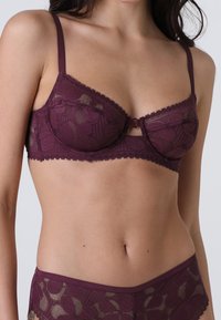 Reggiseno in pizzo borgogna con ferretto, caratterizzato da un motivo floreale, delicate rifiniture lungo i bordi, spalline regolabili e chiusura frontale.