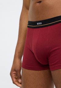 BOSS boxershorts in bordeaux katoen met een zwarte elastische tailleband met witte en gouden logodetails. Soepele textuur en een aansluitend ontwerp.