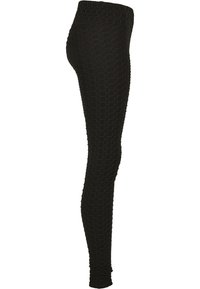 Leggings noirs avec un motif en nid d'abeille texturé, coupe ajustée et large ceinture. Fabriqués en tissu extensible pour le confort et la flexibilité.