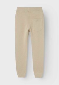 Cremefarbene Sweatpants aus weichem Material, mit einem gerippten Bund und einer einzelnen Gesäßtasche auf der rechten Seite.