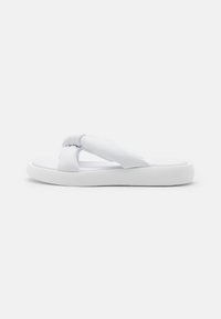Vit flip-flop sandal med knutna tygremmar, platt sula och slät yta. Enkelt design och lätt konstruktion.