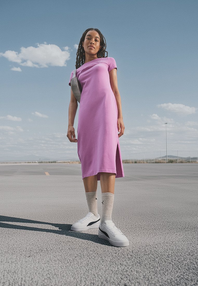 Abito midi aderente rosa con maniche corte e spacco laterale, abbinato a sneaker bianche e calzini grigi chiari, ambientato all'aperto.
