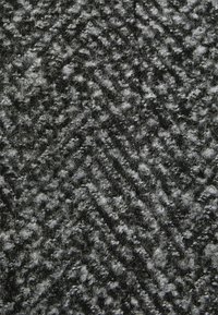 Tecido em preto e cinza com padrão de espinha de peixe texturizado, apresentando fios felpudos, um padrão de ziguezague proeminente, textura suave e superfície irregular.