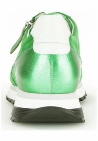 Zapatilla metálica verde con acentos en el talón blancos, que presenta un cierre con cremallera y suela de goma negra texturizada. Diseño minimalista, vista trasera.