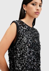 Top senza maniche nero ricoperto di paillettes nere lucide e decorazioni sfaccettate, con scollatura girocollo e vestibilità rilassata.