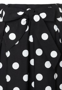 Black fabric skirt with large white polka dots and a tied bow at the waist.