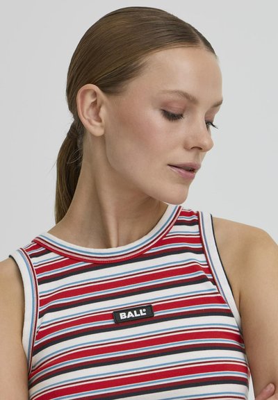 Jeune femme avec les cheveux plaqués en arrière, portant un haut sans manches rayé rouge, blanc, noir et bleu avec une étiquette "BALL", regardant vers le bas à sa gauche.