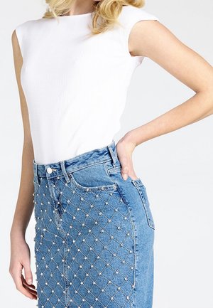 Hvid ribbet ærmeløs top parret med en blå denimnederdel med et tekstureret diamantmønster og perle-lignende detaljer.