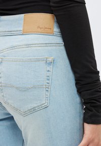 Ανοιχτό μπλε τζιν παντελόνι με δερμάτινο λογότυπο στη μέση στο πίσω μέρος. Διαθέτει κλασικό σχέδιο τσέπης με αντίθετες ραφές.