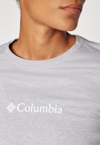 Graues Baumwoll-T-Shirt mit runder Ausschnitt und einem weißen "Columbia"-Logo auf der Vorderseite. Weiche Textur, lässiges Design.