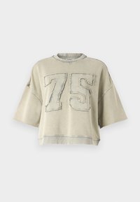 kortärmad, oversized sweatshirt i ljusgrått, med fransade kanter och en framträdande broderad "75" i kontrasterande blått.