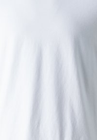 T-shirt en coton blanc avec une texture douce. Il présente un col rond et des manches courtes. Fini lisse sans motifs ni accents visibles.