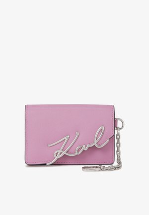 Pink leather wallet with silver chain and hardware. Features a scripted logo on the front. Rectangular shape with a smooth texture.