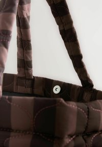 Gestepptes braunes Tote Bag aus gemustertem Stoff in unterschiedlichen Farbtönen, akzentuiert mit rosafarbenen Nähten und einem silbernen Druckverschluss.
