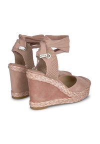 Chaussures compensées en daim rose avec des accents tissés et des sangles enveloppantes en tissu. La semelle présente une texture en jute tressé pour plus de détails.