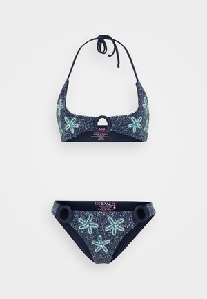 Navy bikini set made of textured fabric, featuring starfish patterns in light blue accents, halter top with circular hardware, and matching bottoms.