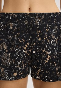 Černé šortky s výrazným leopardím vzorem v odstínech béžové, bílé a hnědé. Měkký materiál s elastickým pasem pro pohodlí.