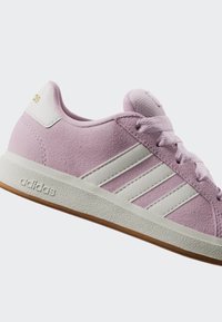 Light purple Adidas sneaker with white stripes, white sole, and brown bottom, shown in side view on a plain background.