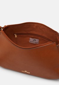 Ruskea nahkalaukku, jossa on sileä pinta, varustettuna kultaisella vetoketjulla ja sisäisellä vetoketjutaskulla. Sisäpuolella merkintä "ANNA FIELD".