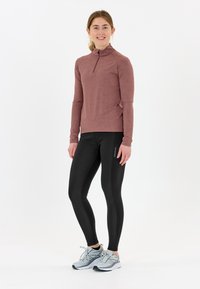 Långärmad, zippered, mauve topp med subtilt blommönster, tillsammans med svarta leggings och ljusgrå löparskor.