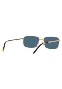 Occhiali da sole rettangolari con lenti blu scuro. Montatura in metallo dorato con accenti neri e tartaruga sulle aste. Cuscinetti per il naso trasparenti attaccati.