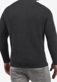 Maglione grigio scuro lavorato a maglia con trama a coste, collo rotondo e maniche lunghe. Presenta un orlo dritto e aderisce al corpo.