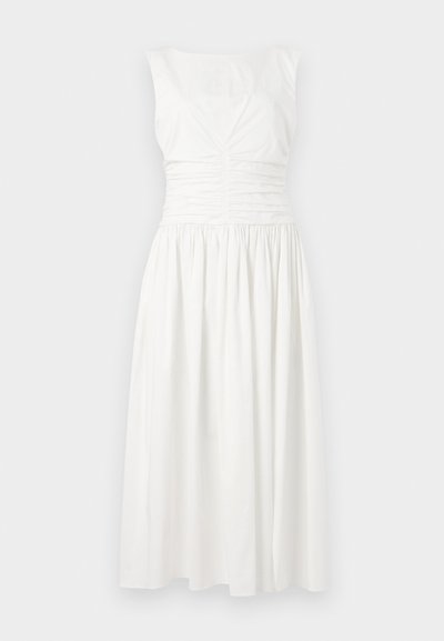 Balta be rankovių suknelė su surinkta liemenėle, lygiuoju paviršiumi ir laisvai krentančia sijona, kuris siekia iki pusės blauzdos.