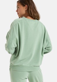Mint green oversized sweatshirt with ribbed collar and cuffs, featuring a soft texture and relaxed fit, styled with matching bottoms.