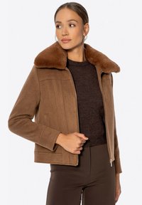 Braune Fleecejacke mit einem Kragen aus Kunstpelz, Reißverschluss und Seitentaschen. Die Jacke hat ein strukturiertes Design und eine taillierte Silhouette.