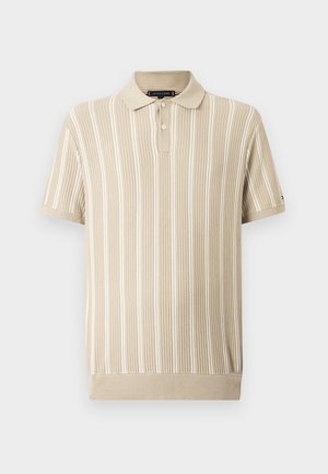 Beige polo-paita, jossa on pystysuorat valkoiset raidat, ribbikuvio ja lyhyet hihat. Varustettu kaksipainikkeisella napituksella ja neulotulla kauluksella.