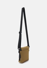 Khaki crossbody bag with a black adjustable strap, rectangular shape, textured fabric, and zipper detail on the side.