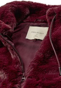 Bordeaux nepluizige jas heeft een soepele voering, een ritsluiting en een label met "FREE/QUENT" in een kleine maat.