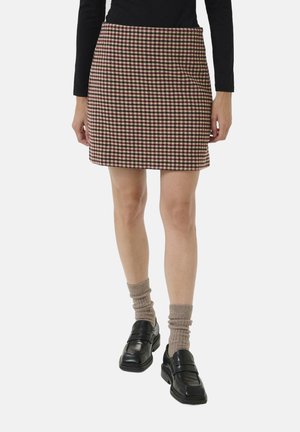 Karierte Minirock in Braun, Creme und Burgunderrot. Schlanker Schnitt mit glatter Textur, kombiniert mit schwarzen Loafers und strukturierten beigen Socken.