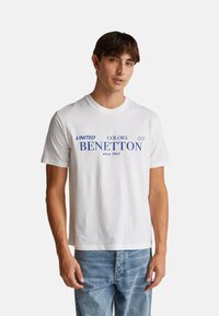 Bílý bavlněný tričko s modrým textem "UNITED COLORS OF BENETTON since 1965." Standardní střih s kulatým výstřihem a krátkými rukávy.